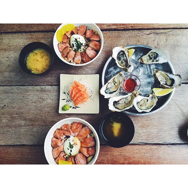Tanuki Raw happy hour spread — donburi bowls, oysters on ice and salmon sashimi